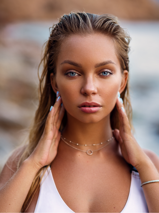 A blonde woman with her hands on her face looking into the camera