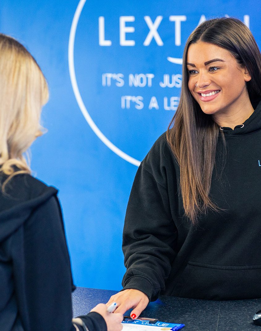 A dark hair woman serving a blonde haired woman at a lextan shop